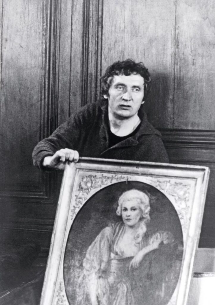 Black and white still of a man holding a framed oval portrait, from the cinema of Walerian Borowczyk