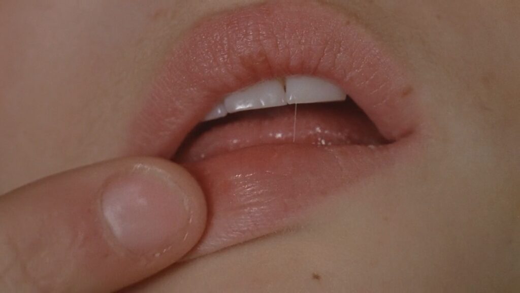 Extreme close-up of a finger touching parted lips in Contes immoraux (1974)