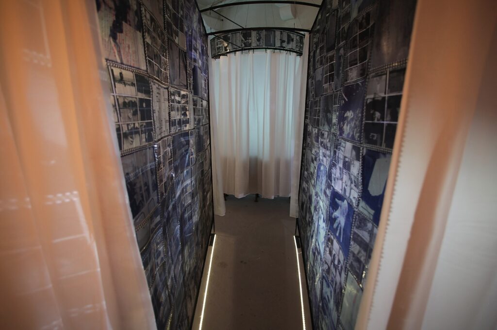 The corridor of transparent archival photographs in Spoor by Natasha Bourke